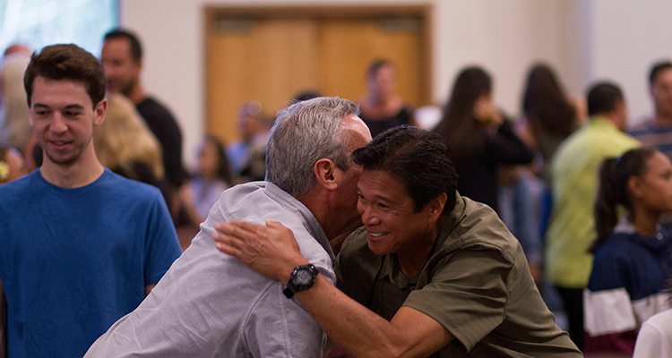 Men embracing in room of people