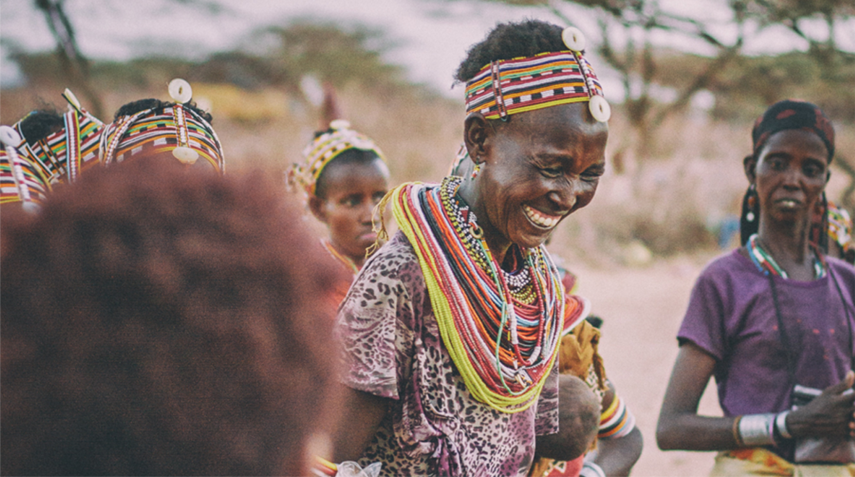 A group of women gathered around and smiling.