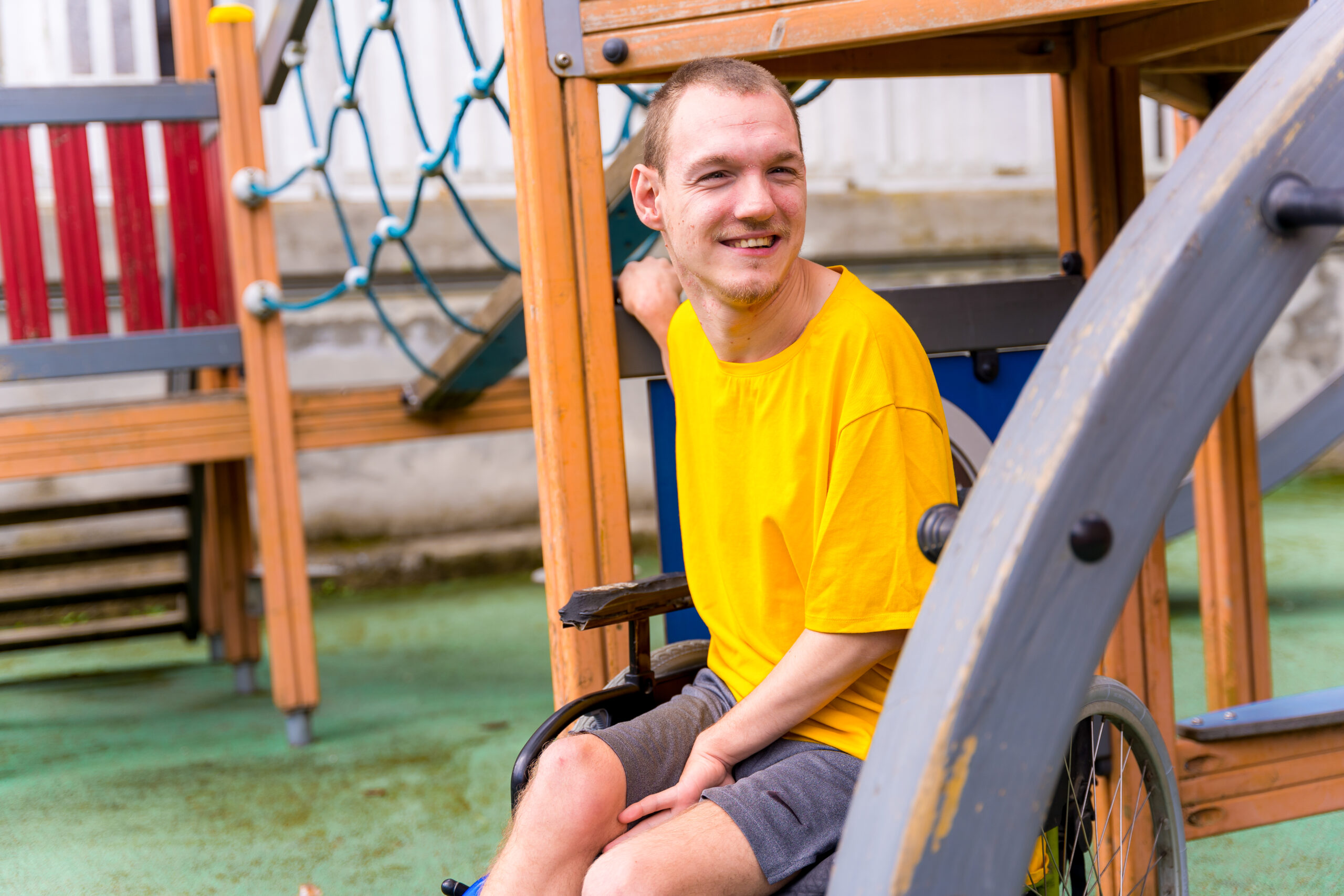 A disabled person in a wheelchair on the swings of a playground