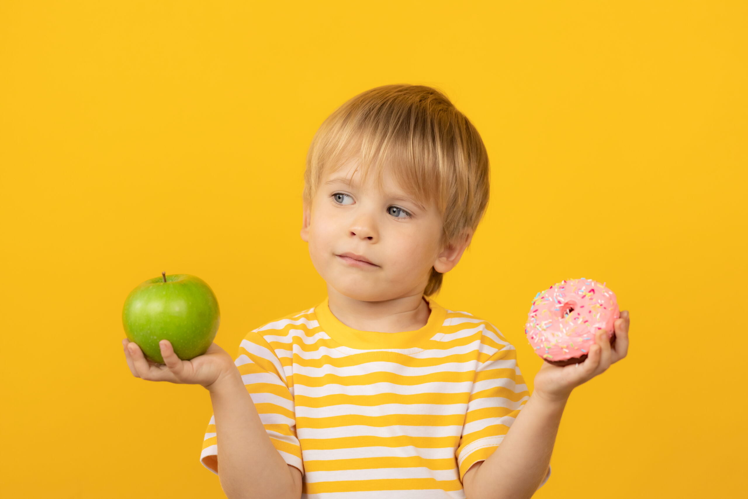 Happy child holding donut and apple